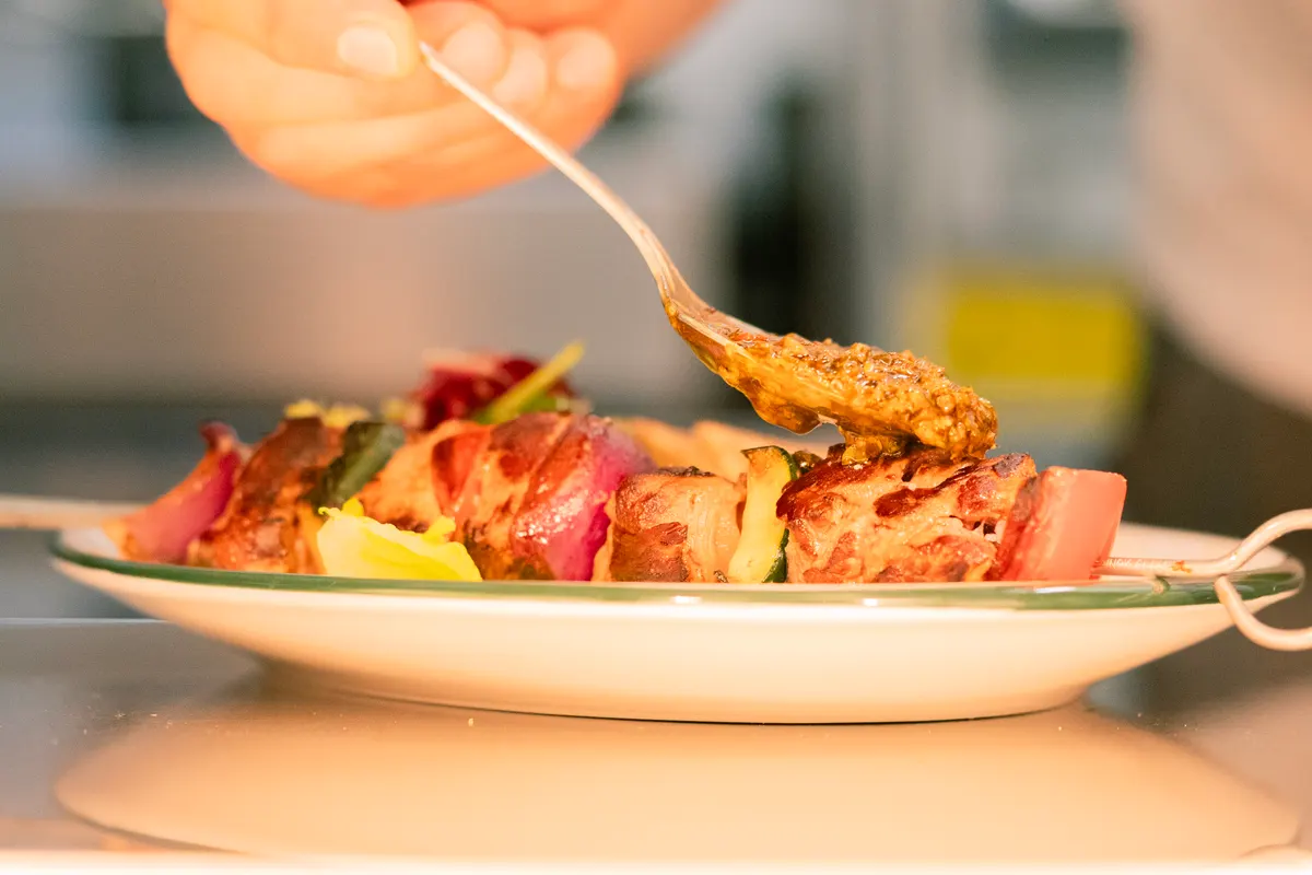 Grillspyd med grøntsager og chili løftes over tallerkenen
