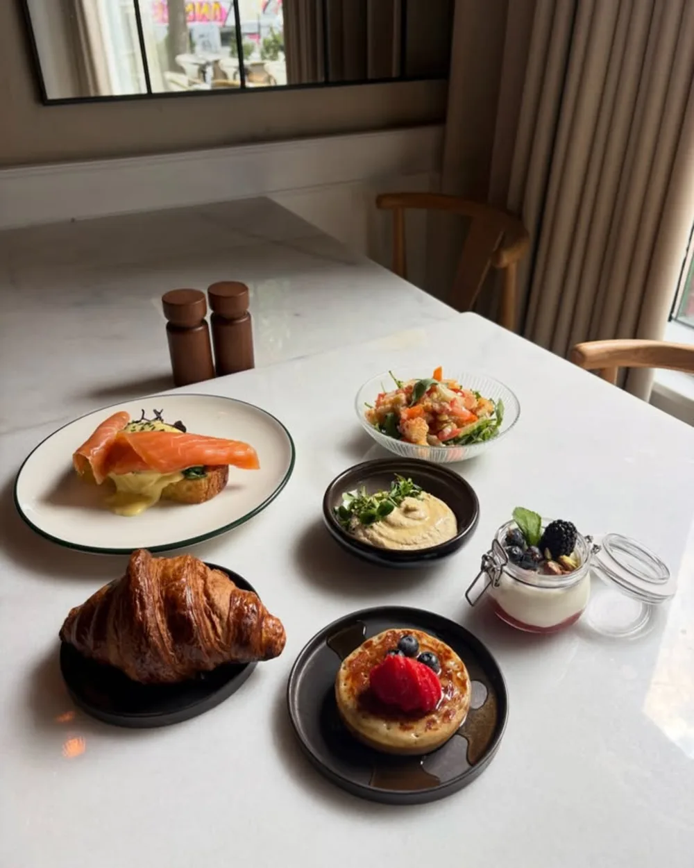 Brunchbord hos CAVU med croissant, røget laks, salater, hummus og yoghurt med bær