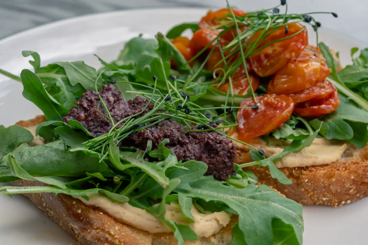 Hummus toast med rucola, syltede tomater og oliventapenade